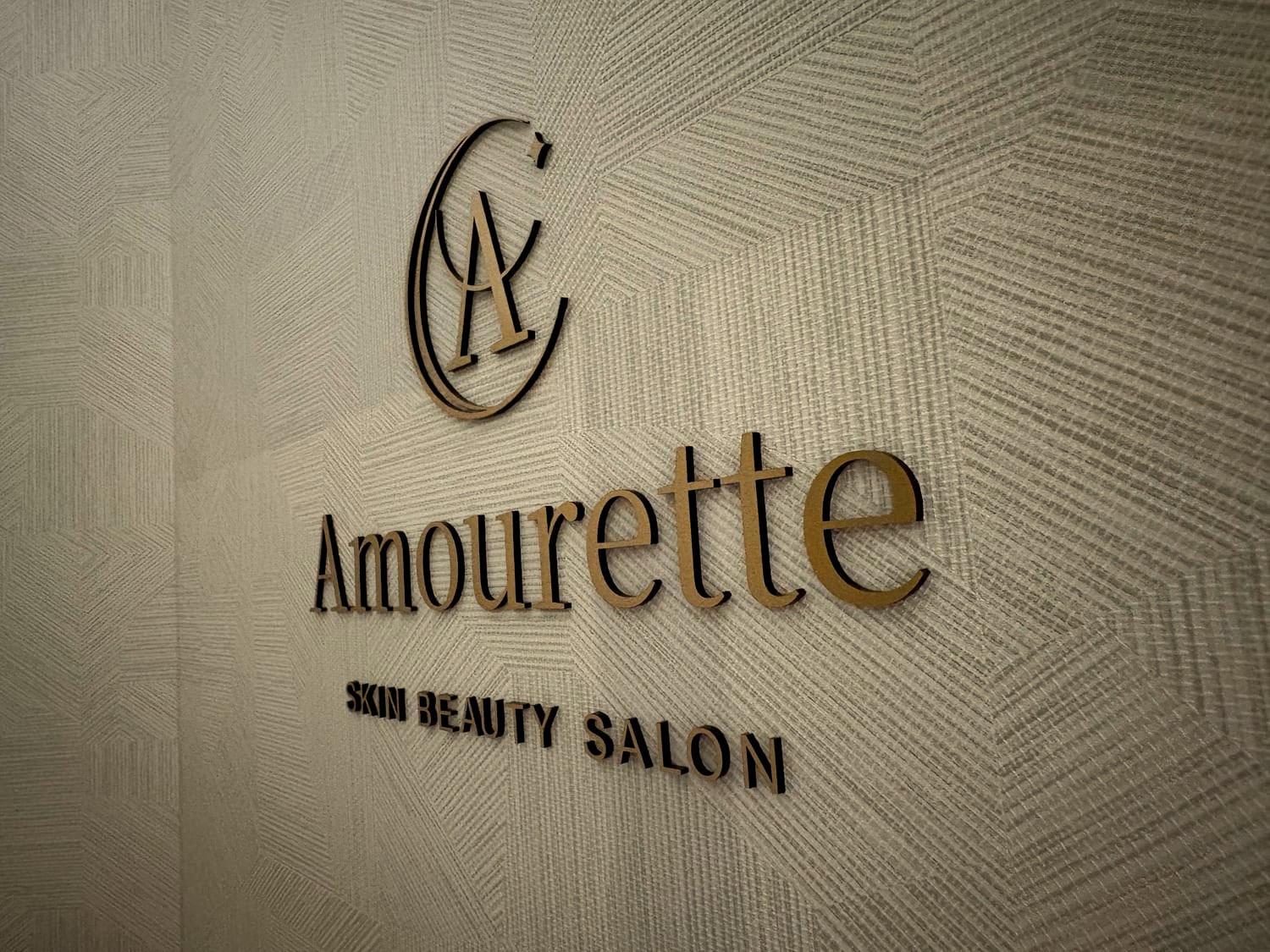 壁面のゴールドの Amourette ロゴ